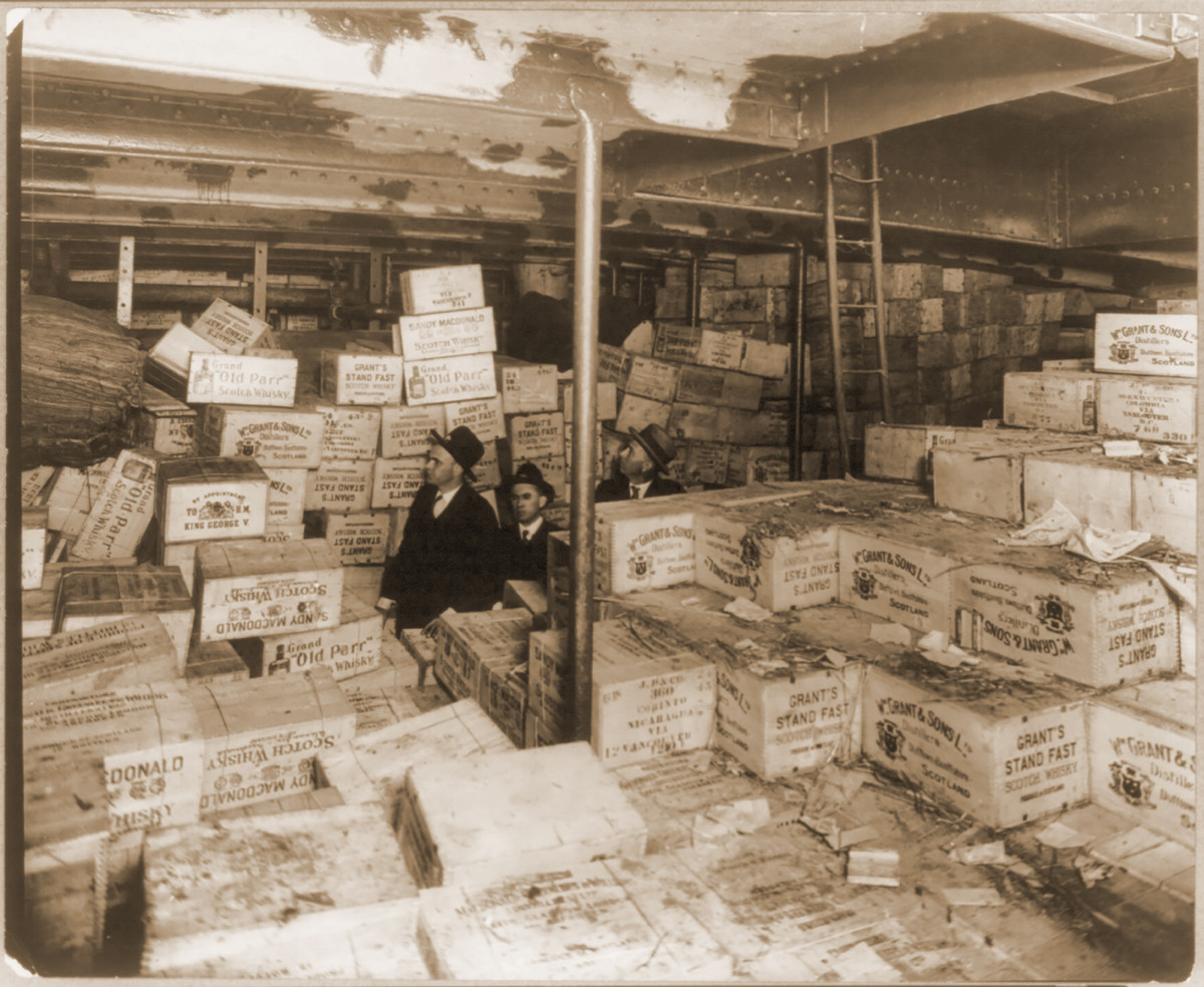 Agents surrounded by cases of alcohol in the hold of an impounded ship.
